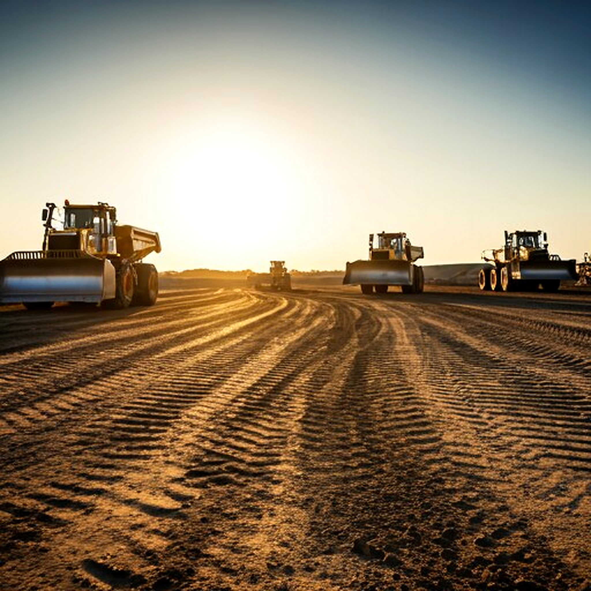 Excavation and site preparation machinery working on a graded construction site.