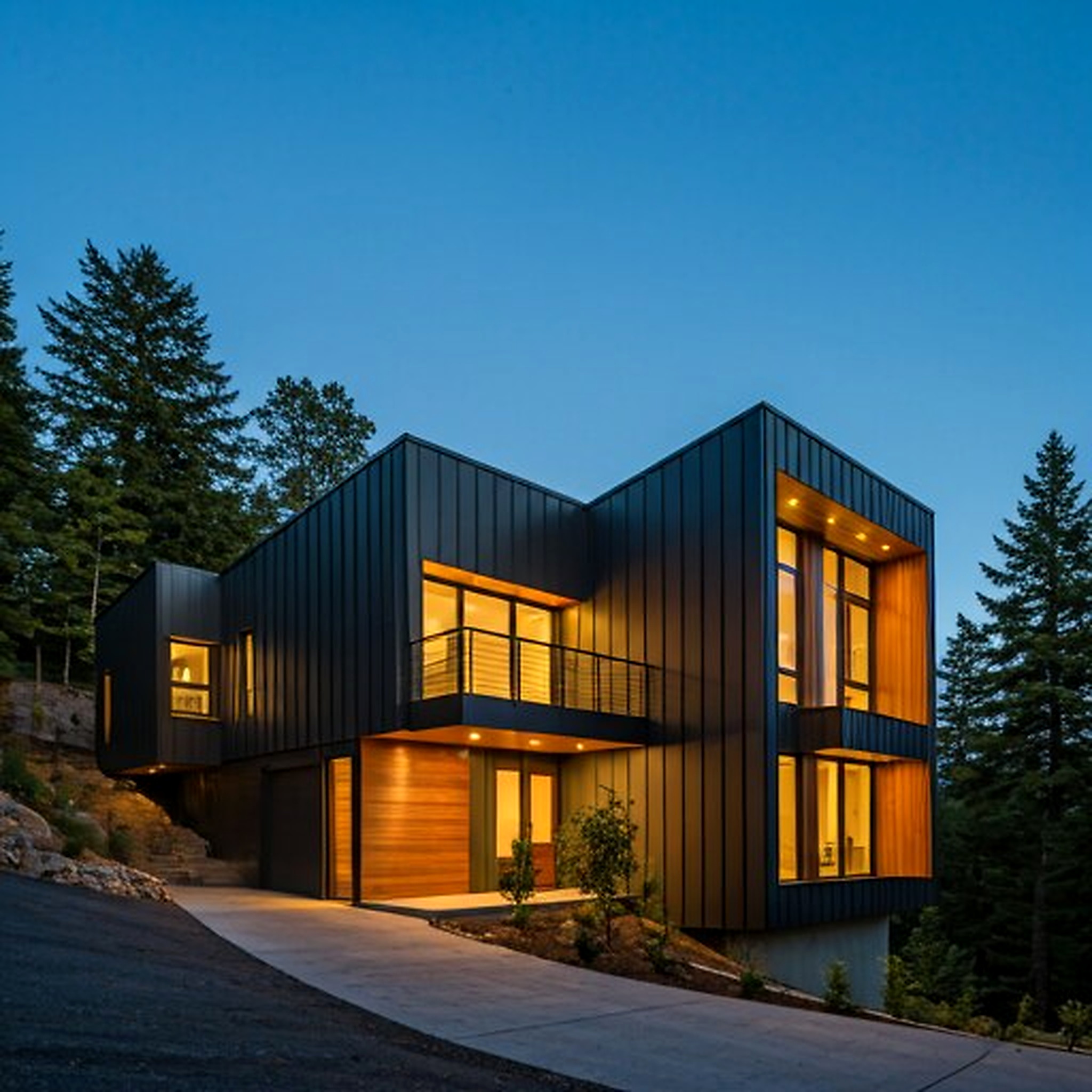 External view of Cedar Ridge Residence, a multi-level architectural home with flat roofs and large overhangs. The facade combines dark charcoal metal panels with warm cedar siding, glowing with internal amber lighting against a twilight blue sky. The environment is a forested hillside, captured with sharp focus and professional architectural photography style.